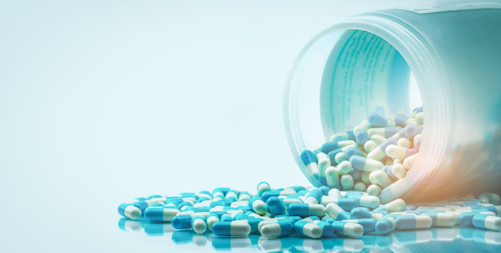 Blue,And,White,Capsules,Pill,Spilled,Out,From,White,Plastic