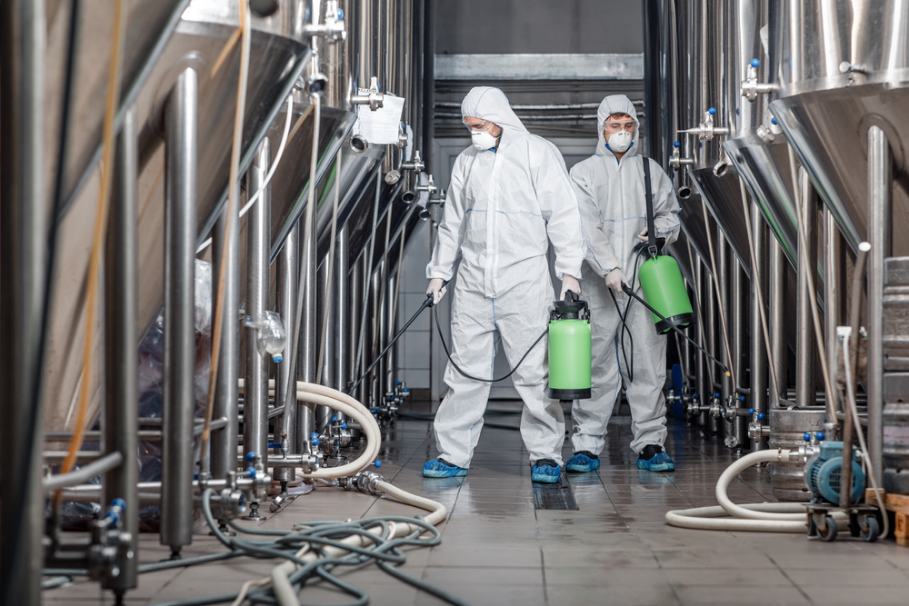 men in protective suit disinfecting a milking process industry by spraying