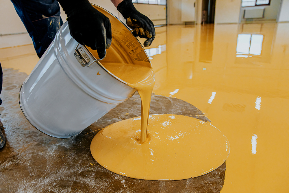 A,Construction,Worker,Apply,Epoxy,Resin,In,An,Industrial,Hall