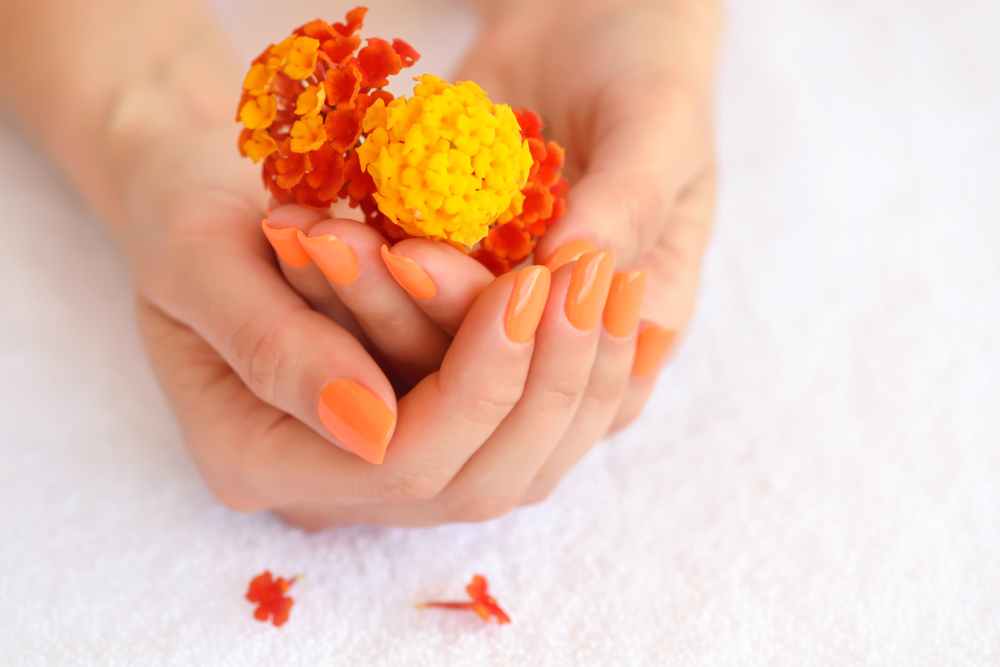 Hands,Of,A,Woman,With,Orange,Manicure,On,Nails,And