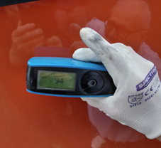 tool in hand to measure gloss level on yacht's hull
